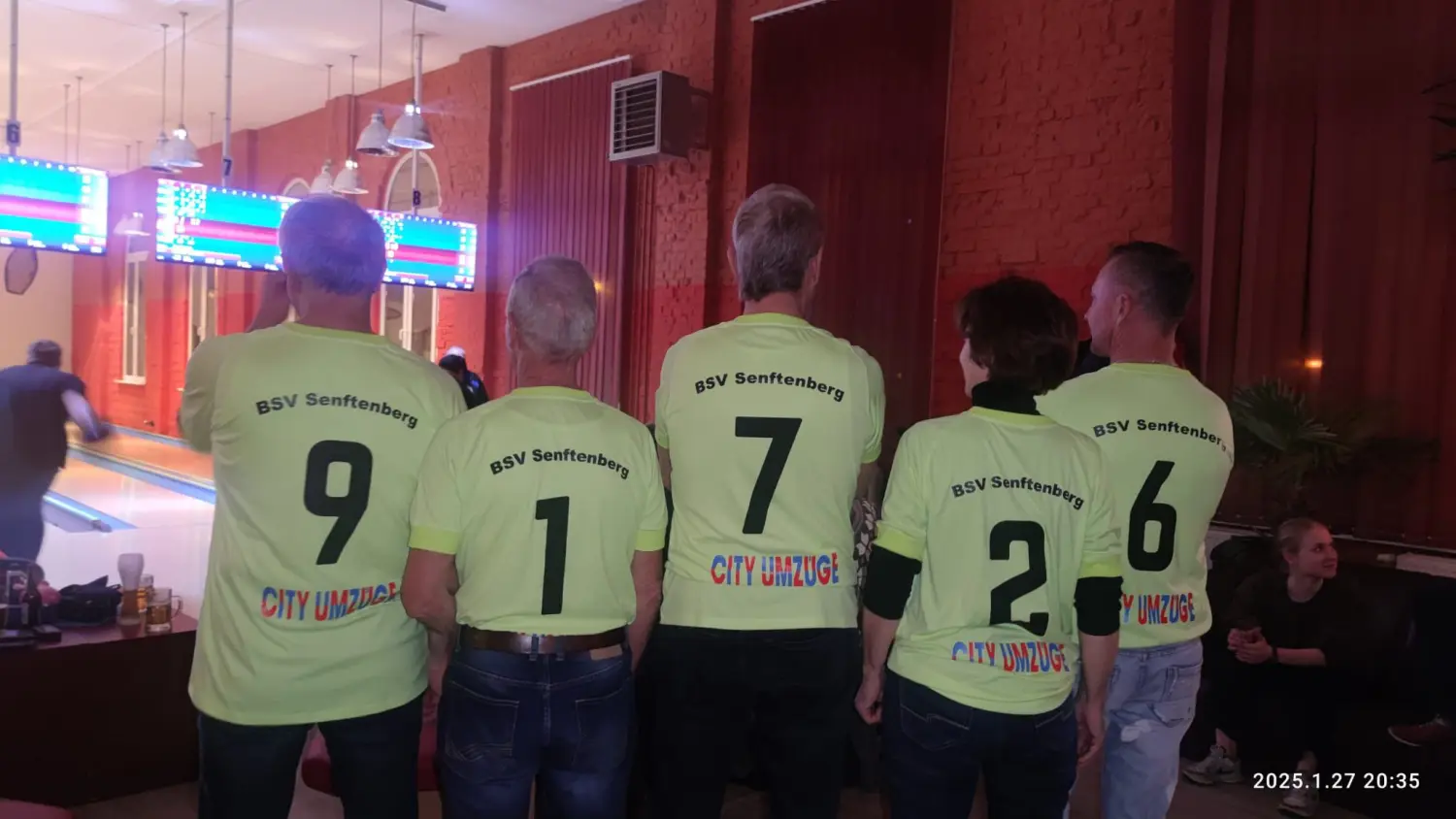 Strike Bowling & Bar – Viele Männer und Frauen stehen im Bowlingclub und tragen Bowling-Sportkleidung